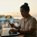 Pessoa usando celular e notebook em Manaus com ícones de Wi-Fi e cadeado